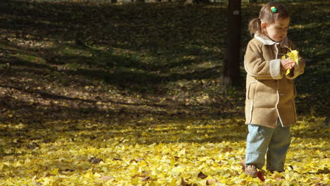 Young-girl-of-Korean-Ukrainian-descent-plays-in-autumn-leaves,-slow-motion