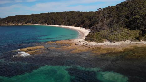 Aerial-view-overlooking-the-rocky-shore-of-Jervis-bay,-New-South-Wales,-Australia---rising,-pull-back,-drone-shot