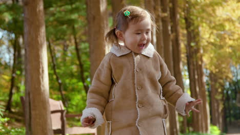 Playful-Little-Girl-Jumps-in-Autumn-Park