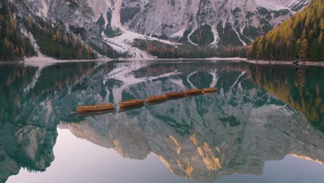 Incredible-Aerial-View-of-Row-Boats-on-Lake-Braies,-Mountain-Reflection-in-Water