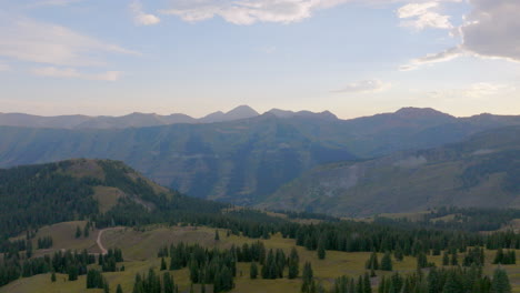 Aerial-view-of-ridge-line-in-the-Colorado-Rockies-with-a-pan-left-to-reveal-a-hiking-trail-and-mountain-range