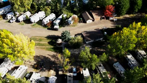 aerial-pan-shot-of-an-RV-park-in-the-fall-with-many-campers-along-the-road,-parked-on-a-campground