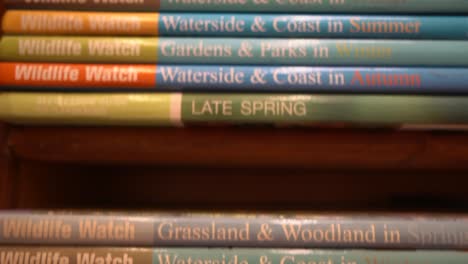 Close-up-tracking-down-shot-of-wildlife-watch-book-volumes-stacks-in-the-wooden-rack