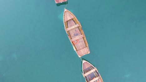 Drone-Flies-Over-Wooden-Row-Boats-on-Famous-Lake-Braies,-Italy-in-Dolomites