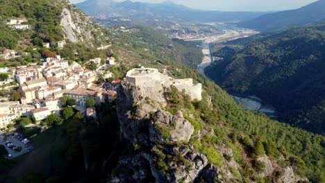 Flying-around-the-castle-of-Gilette,-typical-village-in-south-of-france,-with-houses,-mountains-and-river-in-the-valley