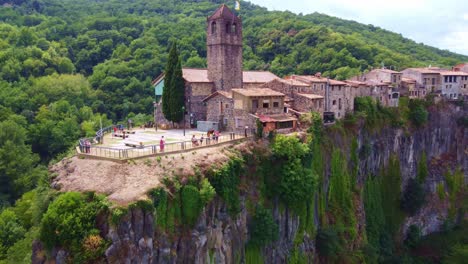 Flying-away-from-a-church,-and-the-view-point-in-Castellfollit-de-la-Roca,-typical-village-in-Catalonia,-Spain