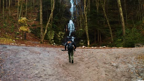Photographer-and-hiker-approaching-a-waterfall-drone-shot