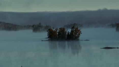 Spectacular-aerial-dawn-fog-surrounds-lake-island
