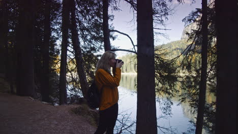Blonde-hair-woman-takes-a-photo-at-Lake-Braies-in-Italy
