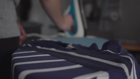 Narrow-focus:-Man-finishes-ironing-striped-shirt-on-ironing-board
