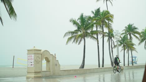 Tropical-Storm,-A-person-rides-a-nike-on-the-empty-beach-on-a-windy-and-rainy-day
