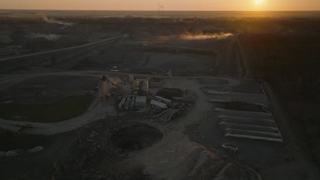 Reversing-cinematic-drone-shot-of-a-stone-quarry-at-dusk-with-stockpiles-and-concrete-equipment-in-foreground