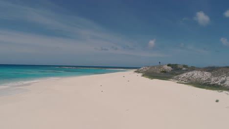 Couple-bathing-in-lonely-caribbean-beach-surrounded-by-white-sand-and-turquoise-water,-drone-shot-Los-Roques-island