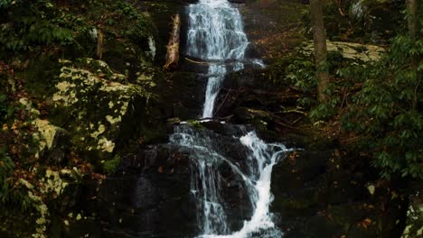 Photographer-hiker-setting-up-tripod-to-take-pictures-of-waterfall