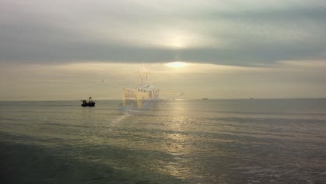 Slow-motion-dronevideo-of-a-fishing-boat-during-a-silver-sunset