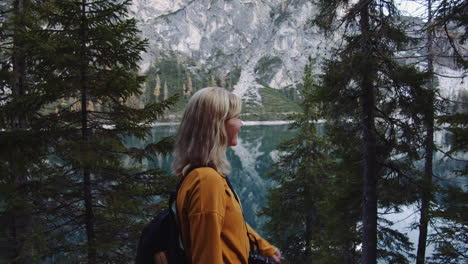 A-blond-haired-girl-walks-along-the-shore-of-the-lake-Braies-laughing,-Dolomites