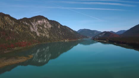 Sylvenstein-Speicher-in-autumn,-scenic-mountain-valley-river-reservoir-lake-with-fresh-blue-water-in-the-Bavaria-Austria-alps,-flowing-down-a-beautiful-forest-along-trees-near-Walchensee