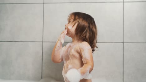Ein-Süßes-Zweijähriges-Mädchen-Spielt-Mit-Badeschaum