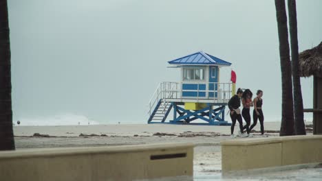 Tropical-Storm,-3-female-leaving-the-empty-beach-on-a-windy-and-rainy-day