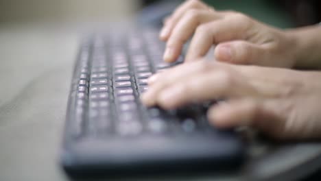 Closeup-image-of-a-business-woman's-hands-working-and-typing-on-computer-keyboard-on-glass-table