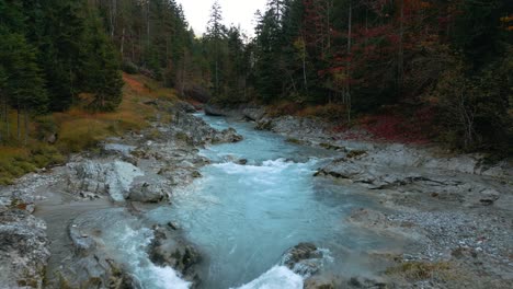 Slow-motion-mountain-river-waterfall-canyon-with-fresh-blue-water-in-Bavaria-Austria-alps,-flowing-along-a-forest-and-trees-near-Sylvenstein-Speicher-and-Walchensee