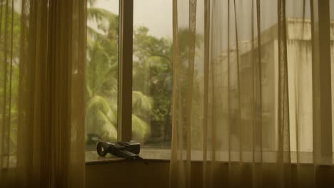 Canon-Super-8mm-Kamera-Auf-Der-Fensterbank-Warmer-Raum,-Goldene-Hitze,-Indien,-Palmen-Im-Hintergrund,-Warme-Durchhänge-Und-Vorhänge-Kamerafotografie-Und-Reisevideo,-Die-Erinnerungen-An-Den-Urlaub-Festhalten