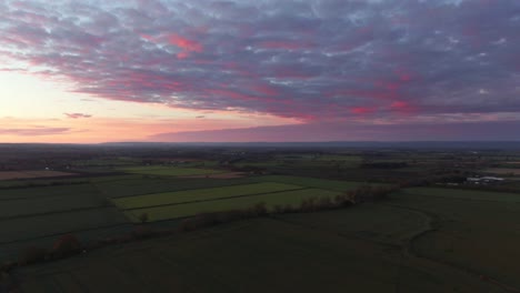 Drohnen-Parallaxe-Eines-Violetten,-Stimmungsvollen-Sonnenuntergangs-über-Einer-Bewölkten-Englischen-Landschaft