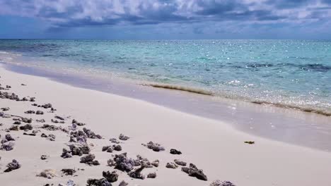 DEAD-WHITE-CORAL-ON-WHITE-SAND-BEACH,-WAVES-BREAK-ON-SHORE-BEACH-CARIBBEAN-SEA