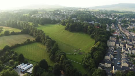 Large-open-public-local-park-with-wavy-green-hills-and-tall-trees-around-from-drone-view