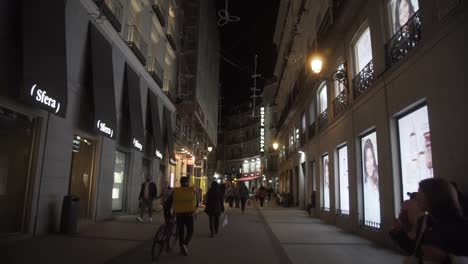 Spanish-street-at-night-with-stores-an-people-walking
