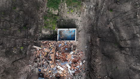 Rising-aerial-view-above-remains-of-pool-and-demolished-house-after-forest-wildfire
