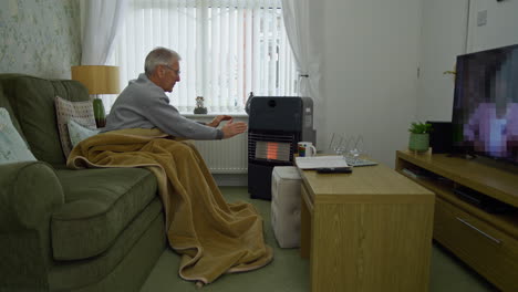 Älterer-Mann,-Der-Versucht,-Sich-Während-Der-Energiekrise-Durch-Ein-Gasfeuer-Warm-Zu-Halten
