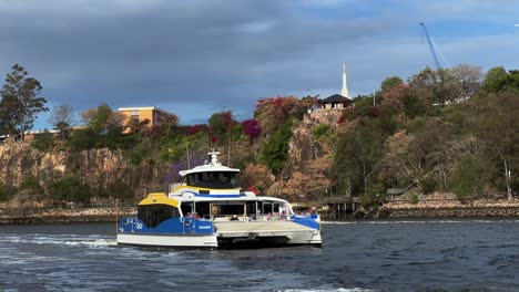 Citycat-ferry-cruising-on-the-river-across-inner-city-suburbs,-passing-by-kangaroo-point-cliff-park-and-under-pacific-motorway-captain-cook-bridge,-Brisbane,-Queensland,-Australia