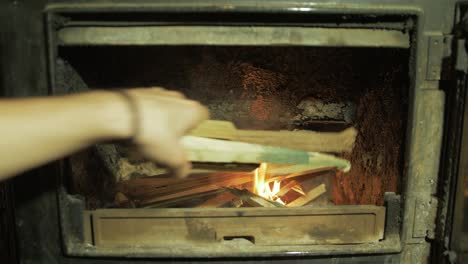 Adding-kindling-sticks-to-wood-burning-stove-fire