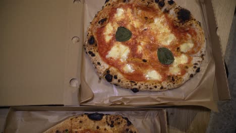 sliding-top-down-shot-of-delicious-Italian-pizzas-delivered-in-boxes-on-the-table