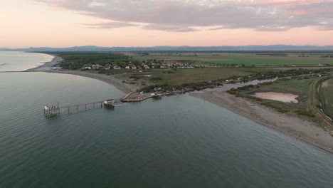 Aerial-view-slow-motion-of-fishing-huts-on-shores-of-estuary-at-sunset,italian-fishing-machine,-called-"trabucco"-Ravenna-near-Comacchio-valley