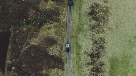 2-off-road-vehicles-driving-down-quiet-secluded-track-from-top-down-aerial-view
