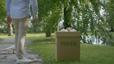 Man-Throwing-Paper-In-Paper-Bin-Near-White-Bird,-Recycling-Purpose