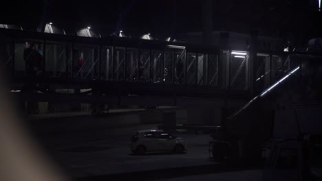 Menschen,-Die-Die-Flughafenbrücke-überqueren,-Um-Nachts-In-Zeitlupe-In-Das-Flugzeug-Einzusteigen