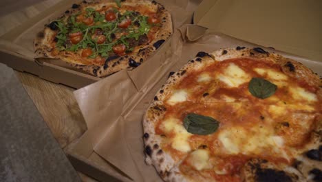 sliding-shot-of-delicious-Italian-pizzas-delivered-in-boxes-on-the-table