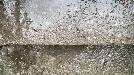Raindrops-On-Concrete-Ground-With-Reflections-On-Puddles