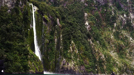Waterfall-falling-from-high-rocky-cliff-in-New-Zealand,-aerial-drone-view