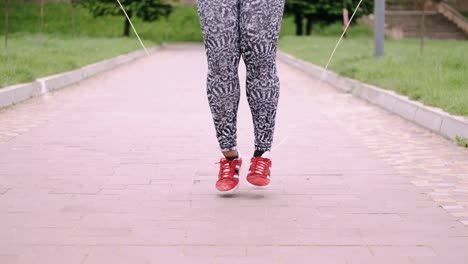 Woman-in-yoga-pants-is-doing-jumping-ropes-outdoors-in-the-park-area