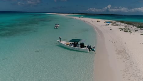 Sailor-and-captain-put-motorboat-anchor-on-sand-to-get-to-caribbean-beach,-tie-up-boat-full-of-tourists,-Los-Roques