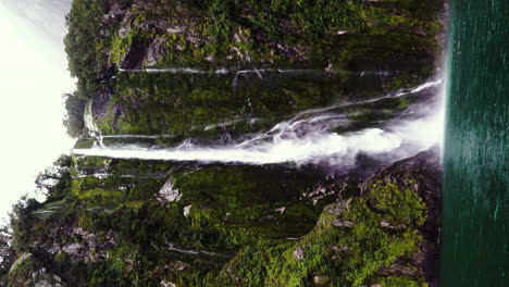 Stirling-Falls-splashing-on-blue-lake-water-surface,-vertical-shot