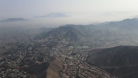 Eine-Neblige-Drohneaufnahme-Einer-Lagune-Und-Hügel-Der-Stadt-Lima