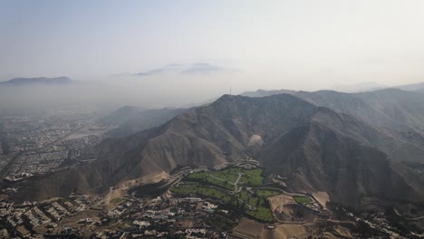 Eine-Drohnenaufnahme-Der-Berge-Der-Stadt-Lima-Auf-Einem-Grünen-Garten
