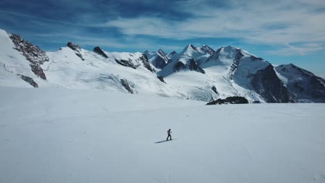 Tracking-Shot-Of-One-Skier-Walking-On-Snow-In-Snowy-Mountains-Landscape,-Alpine