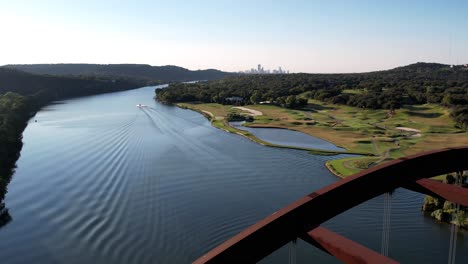 Aerial-drone-backward-moving-shot-flying-above-the-Pennybacker-Bridge-in-Austin,-Texas-along-hillside-at-daytime