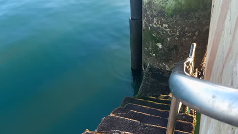 Pequeñas-Escaleras-Que-Descienden-Desde-El-Muelle-Hasta-El-Mar-Con-Una-Protección-De-Hierro